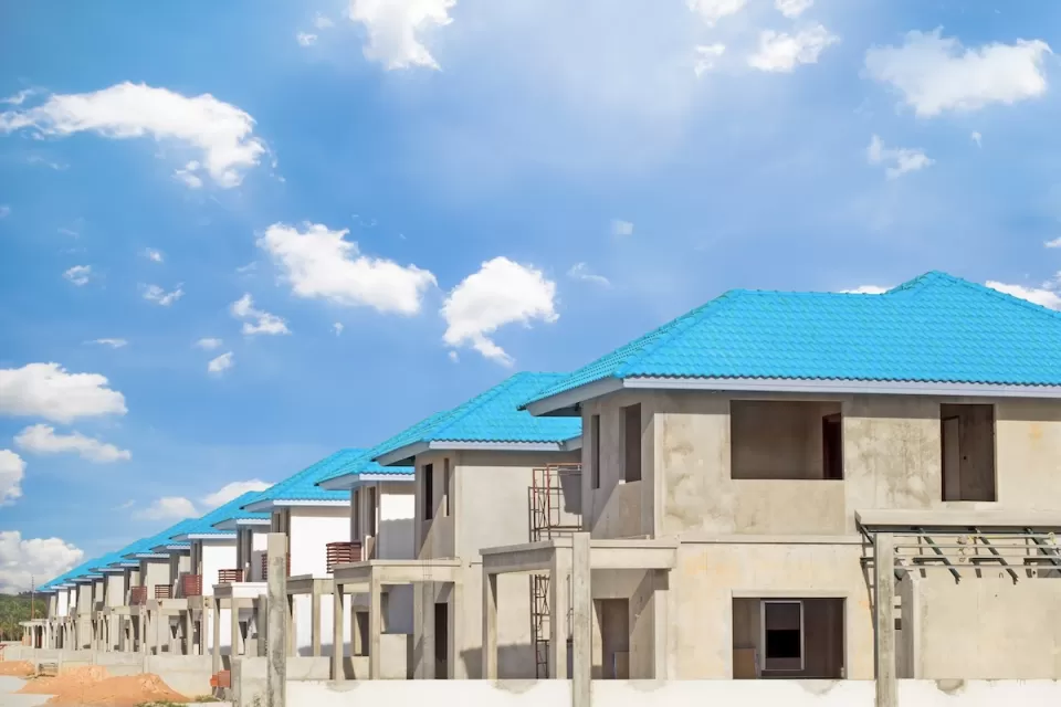 Row of concrete two-story homes with blue tile roofs under construction.